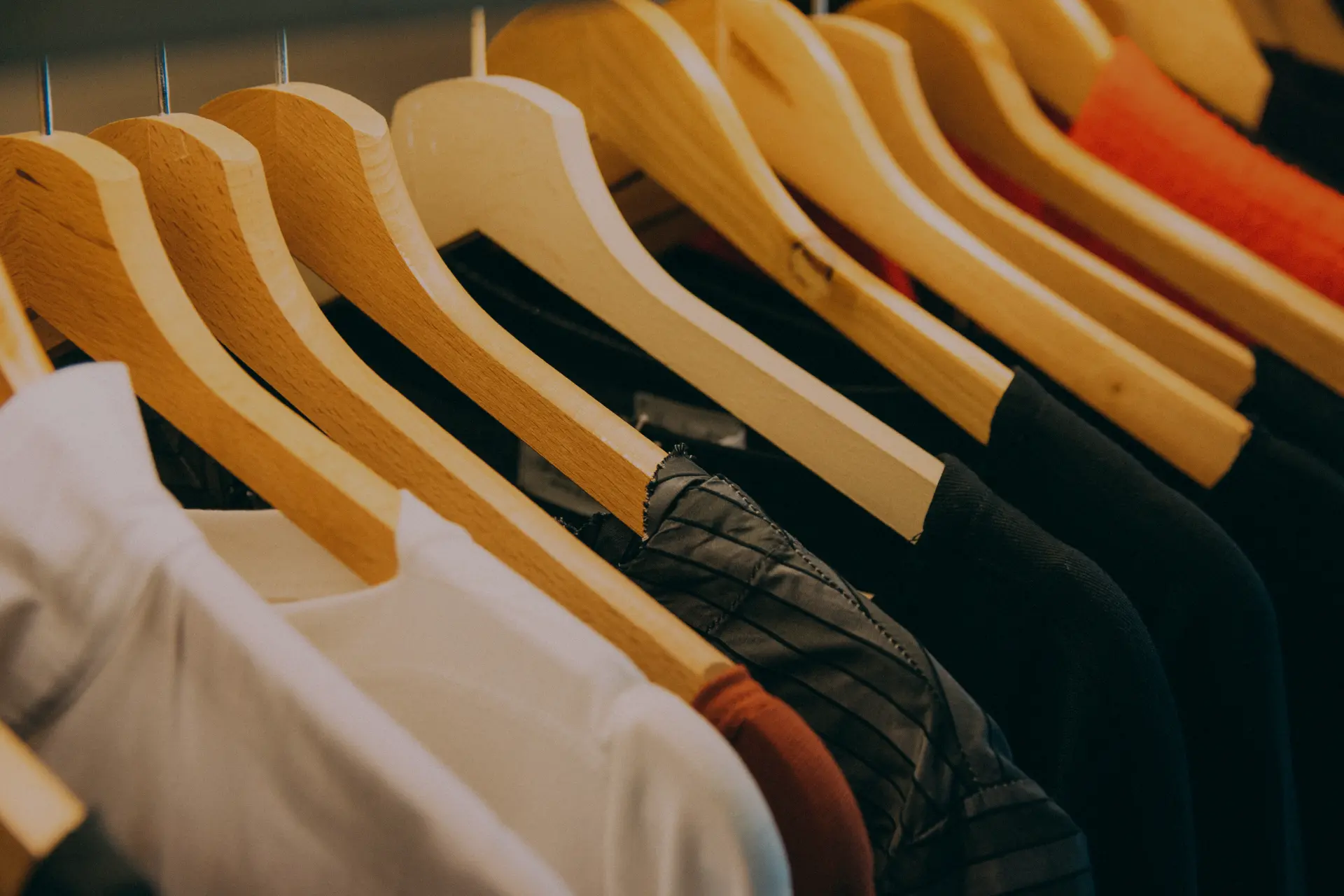 Clothing textures and necklines arranged on wooden hangers